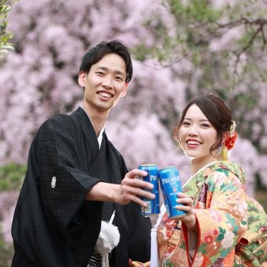 しだれ桜を背に缶ビールで乾杯する紋付袴の新郎と色打掛の花嫁。白鳥庭園で撮る春の桜前撮り