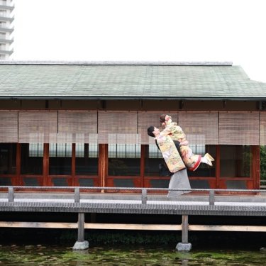 池の上の数寄屋の回廊で花嫁を抱き上げる紋付袴の新郎と色打掛の花嫁。白鳥庭園で撮る春の和装前撮り