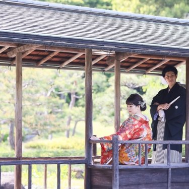 池の上の回廊で座る色打掛の花嫁と立って見守る紋付袴の新郎。白鳥庭園で撮る大人の和装前撮り