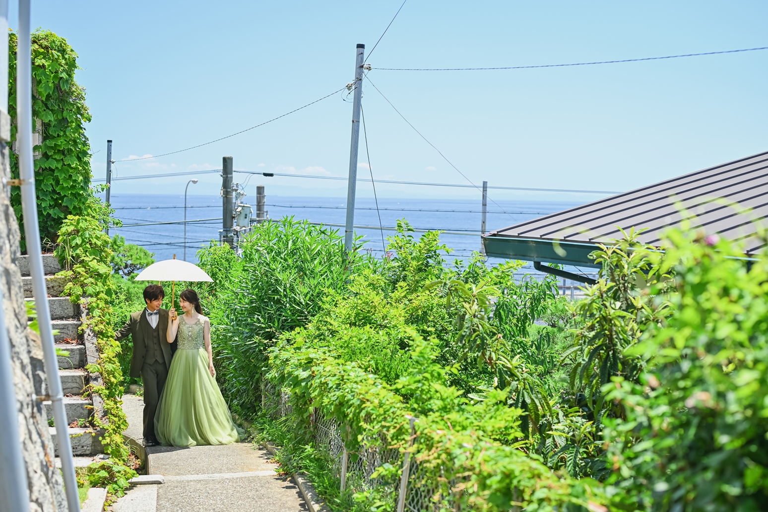 海の見える景色をバックに歩いてる新郎新婦