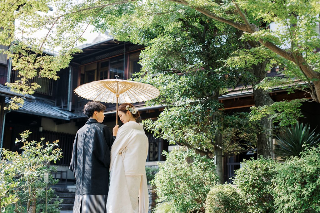 歴史的建造物の前で和傘をさす新郎新婦
