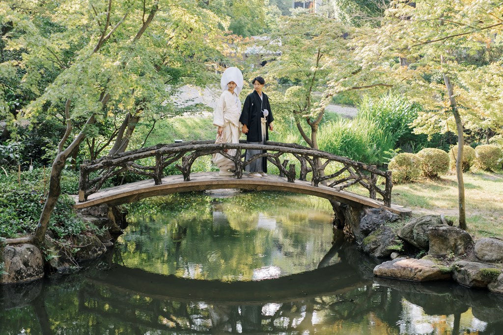 池にかかる橋を歩く新郎新婦