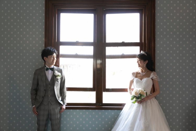 窓際両サイドでお互いを見つめながら立つ新郎新婦