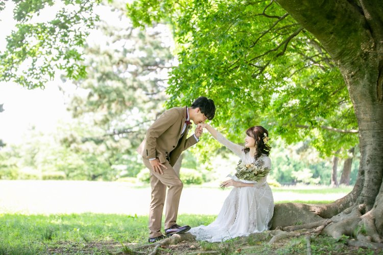 木の下で新婦の手にキス