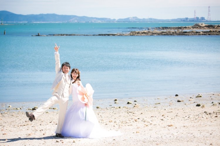 海をバックに楽しそうにポーズをとる新郎新婦