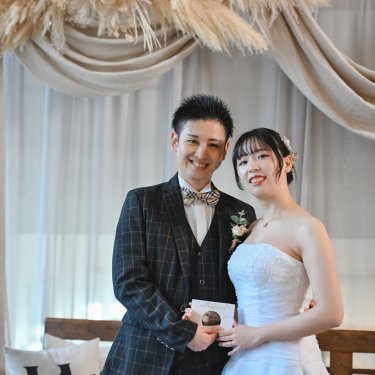 エコー写真を持って寄り添うチェックのタキシードの新郎とウェディングドレスの花嫁。マタニティの前撮り