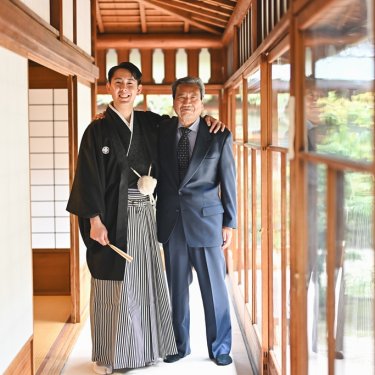 庭に面した廊下で、スーツのお祖父様と肩を寄せる紋付袴の新郎。東山荘の和装前撮りで撮る家族写真