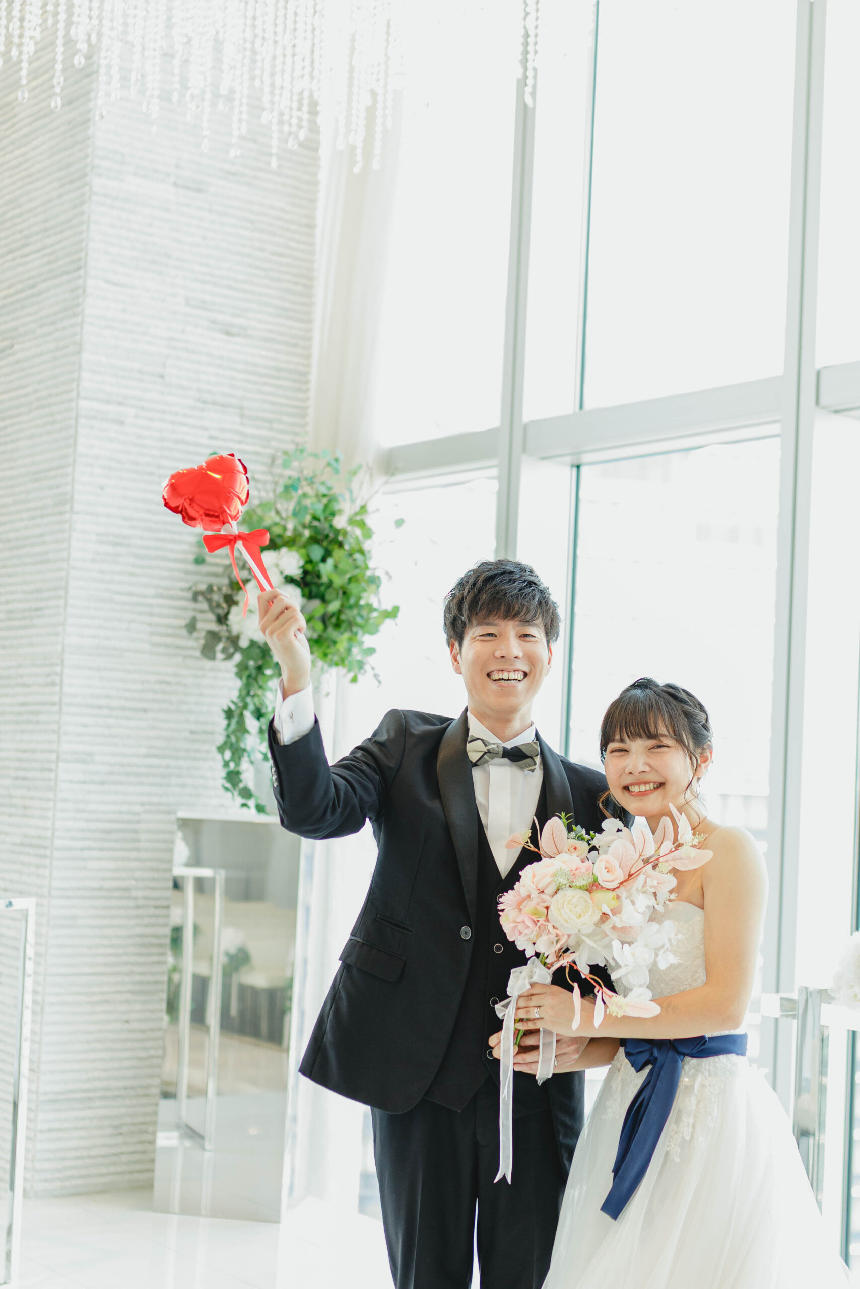 天井まである高い窓越しのウェディングフォト