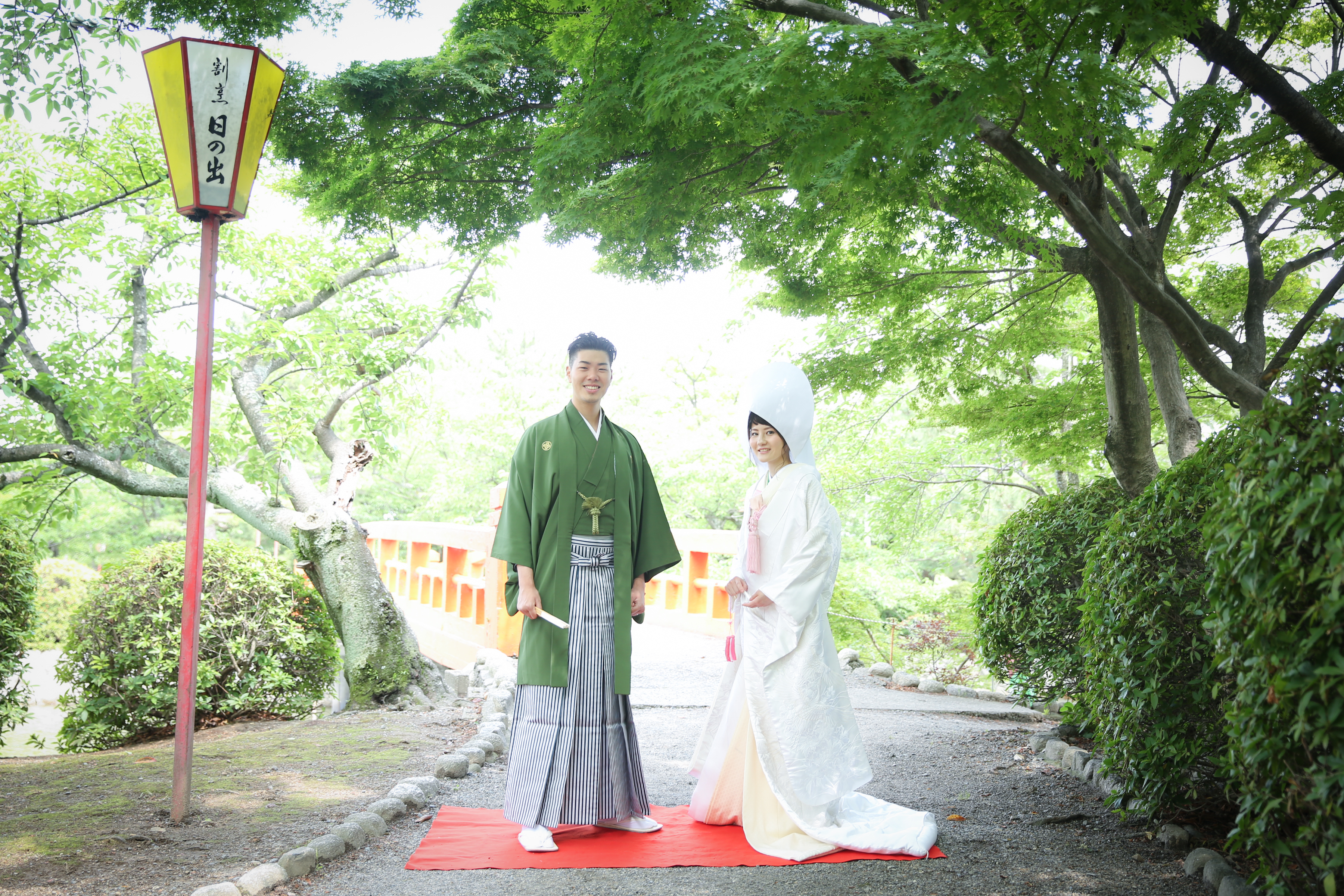 赤い橋の上で寄り添う新郎新婦のメインカット