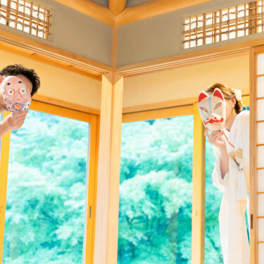 障子から半分顔を出し、お面で顔を隠す紋付袴の新郎と白無垢の花嫁。和室で撮るおちゃめな和装フォトウェディング