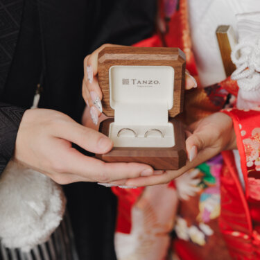 色打掛の花嫁と紋付袴の新郎が二人の手で木製のリングボックスを開き、結婚指輪を見せる手元のカット。和装前撮りで人気の小物ショット