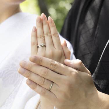 白無垢の胸元で新郎の手に手を重ね、婚約指輪と結婚指輪を見せる花嫁の手元アップ。和装前撮りの定番カット